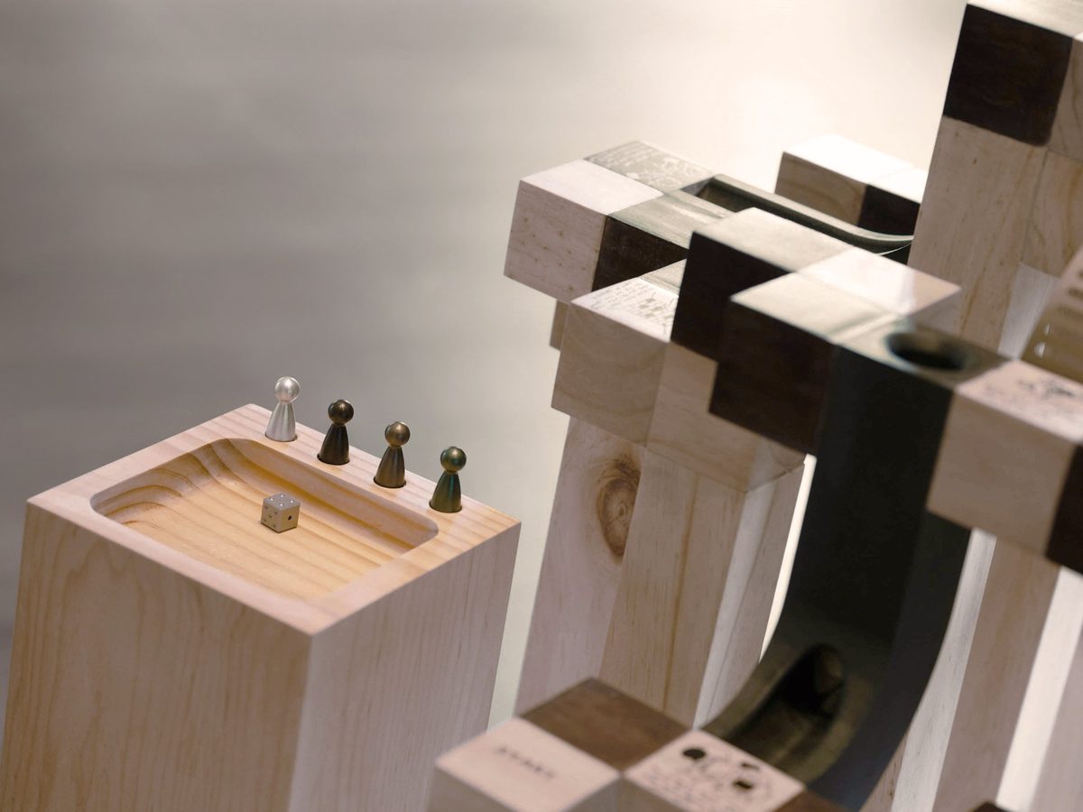 Climbs & Slides — wooden dice totem and aluminium tokens beside the 3D Snakes & Ladders sculpture