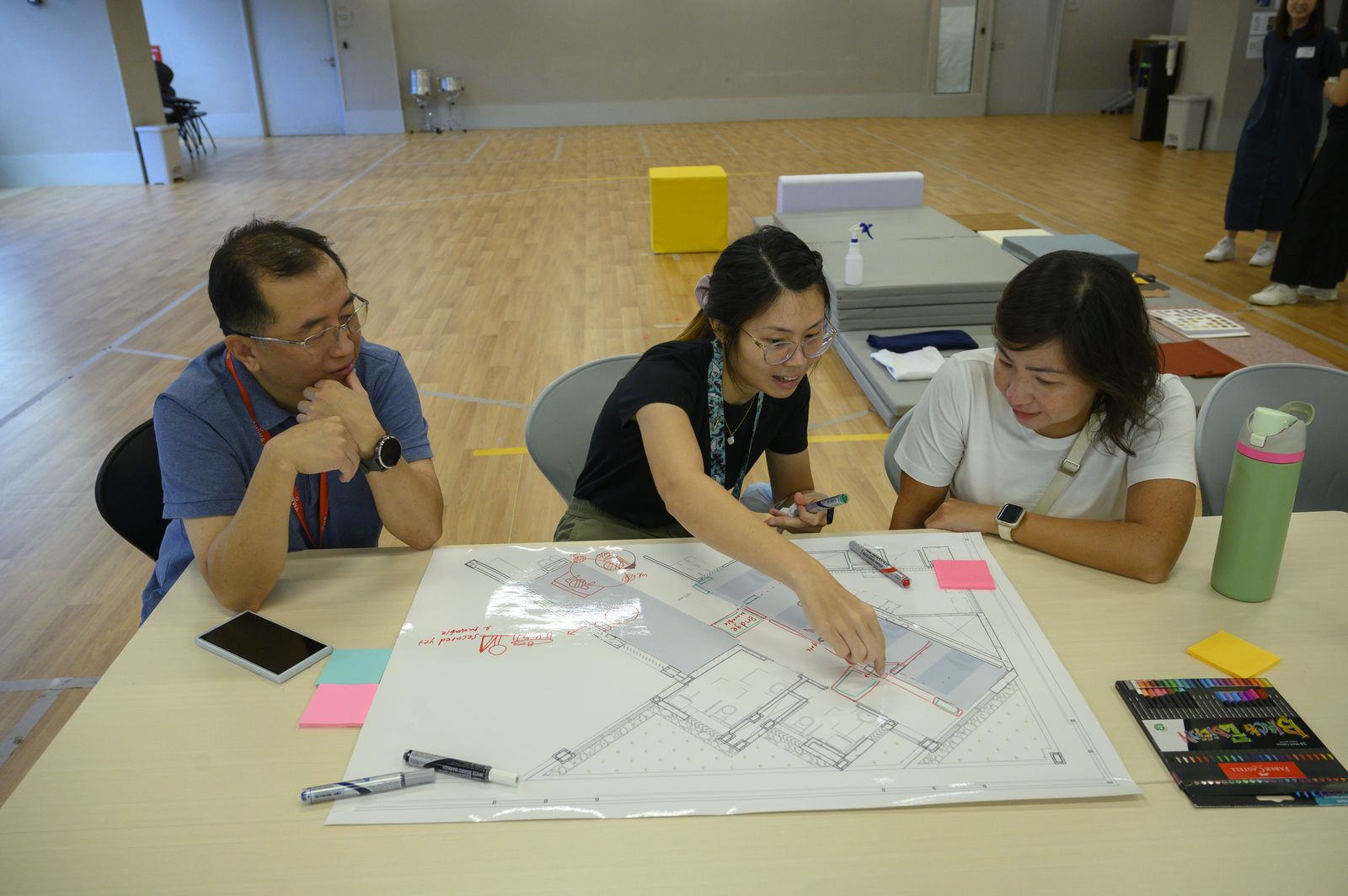 Staff discussing the layout around a table
