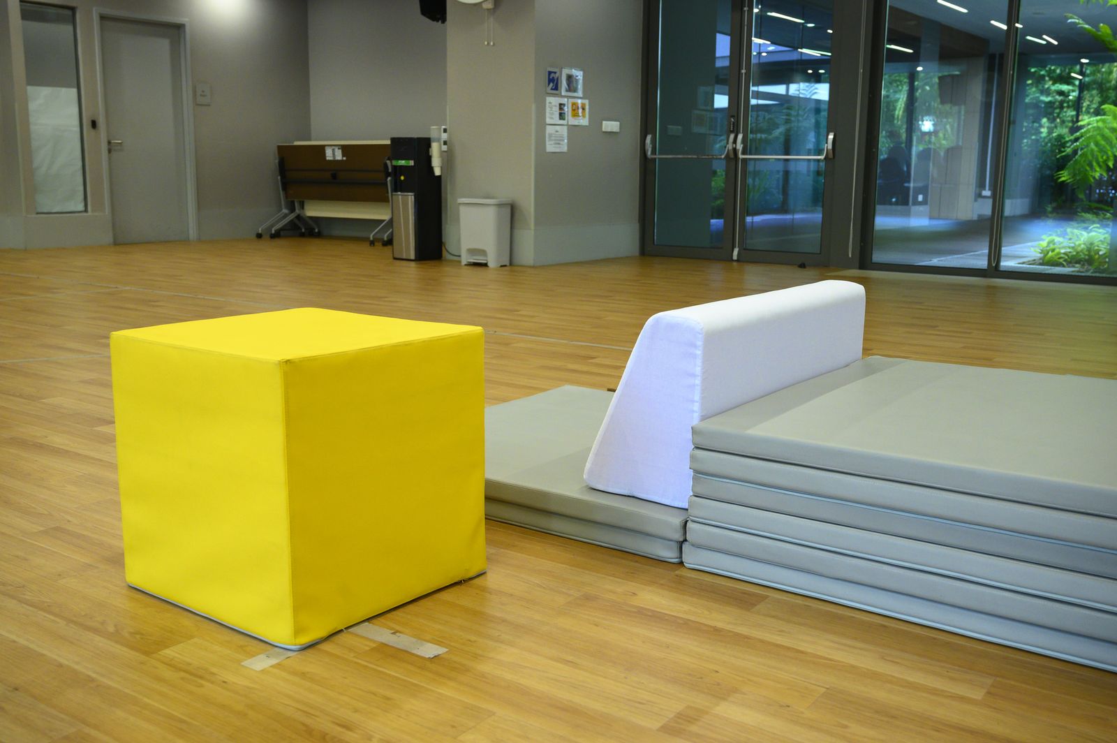 A yellow foam cube and wedge on stacked floor mats
