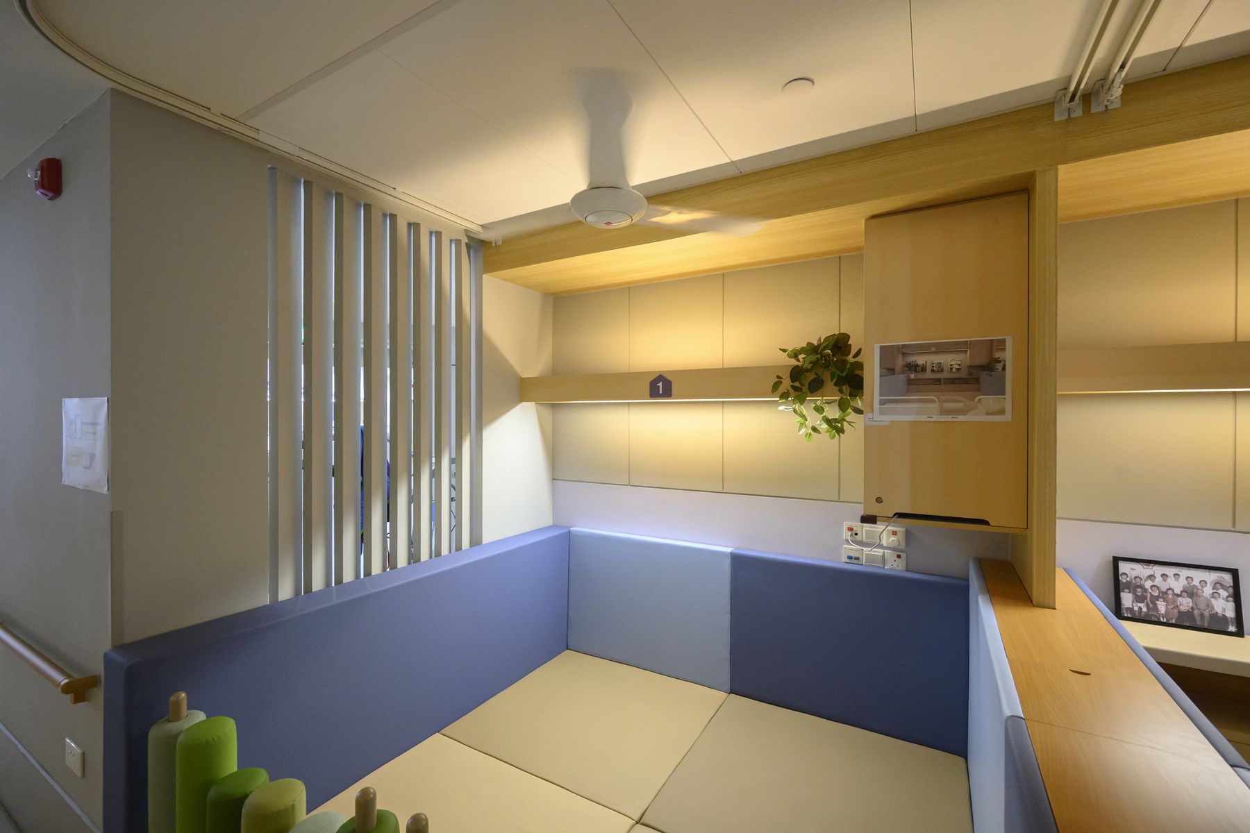 A floor-based bay with soft wall panels and a shelf for personal items