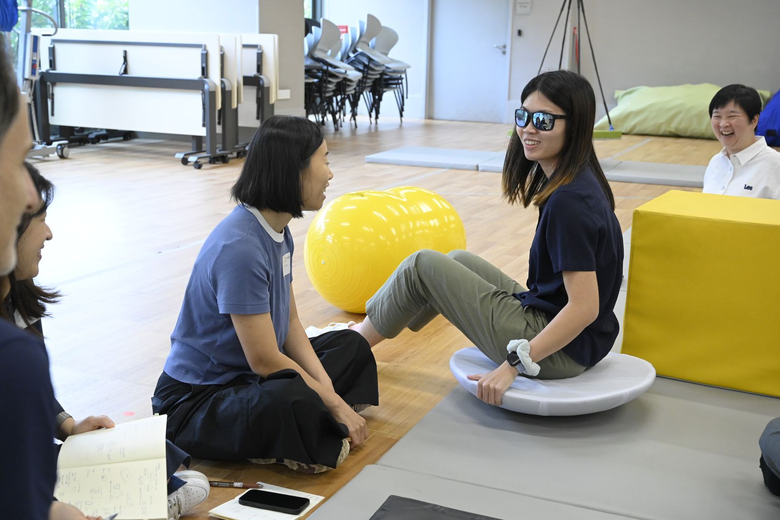 Two team members testing a balance disc and floor cushions