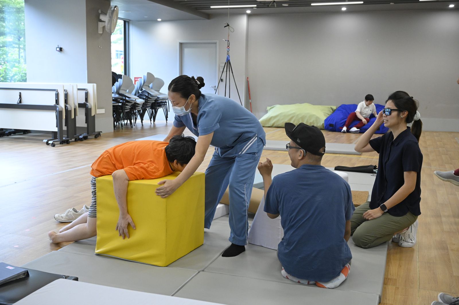 A nurse helping a colleague over a yellow block, simulating a transfer