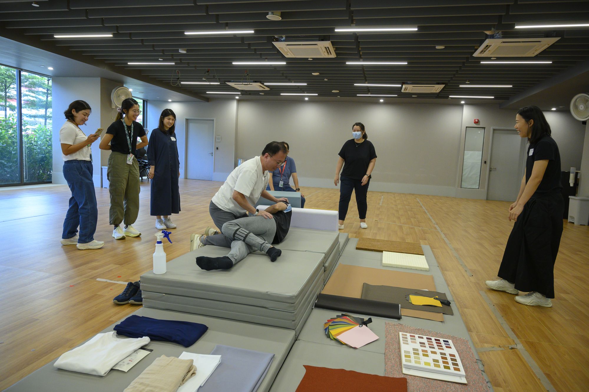 Staff testing foam blocks, mats and material samples laid out on the floor of the activity hall