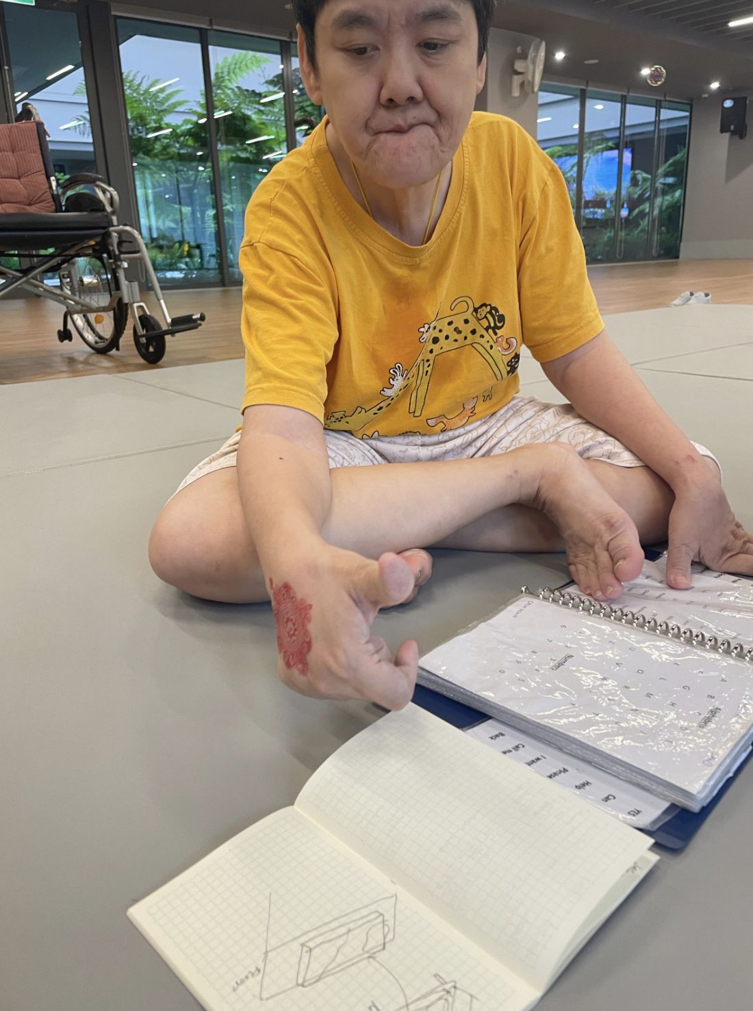 A resident sitting on the floor mat, flipping through a picture book