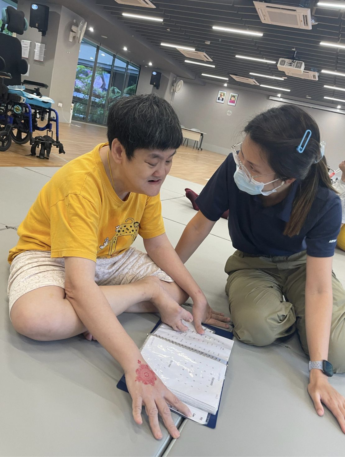 A resident and a care specialist sitting on the floor, looking at a picture book together