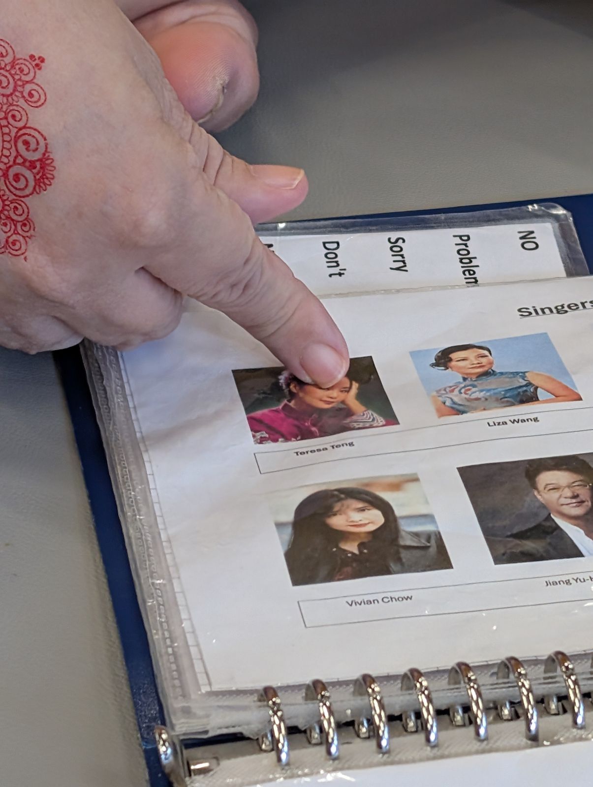 A resident pointing at photos of singers in a picture book