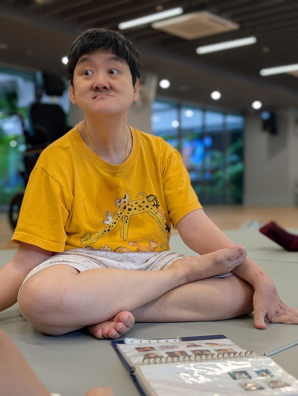 A resident sitting cross-legged on the floor mat