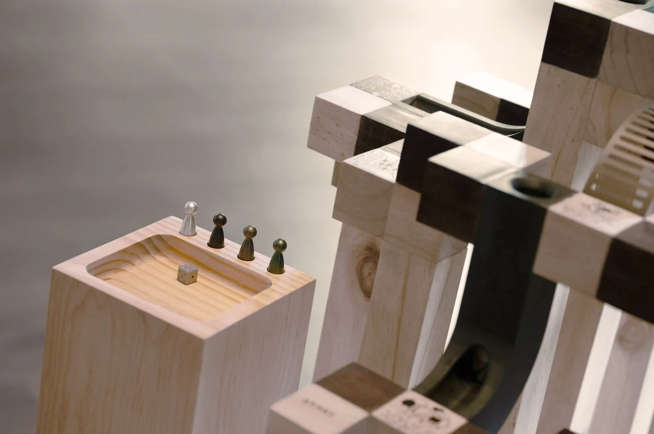 The wooden dice totem and four aluminium playing tokens beside the sculpture.