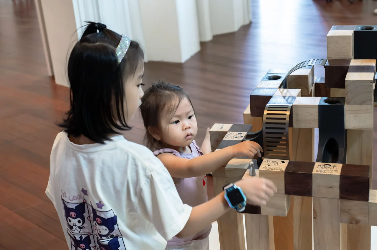Young visitors moving a token along the sculptural game.