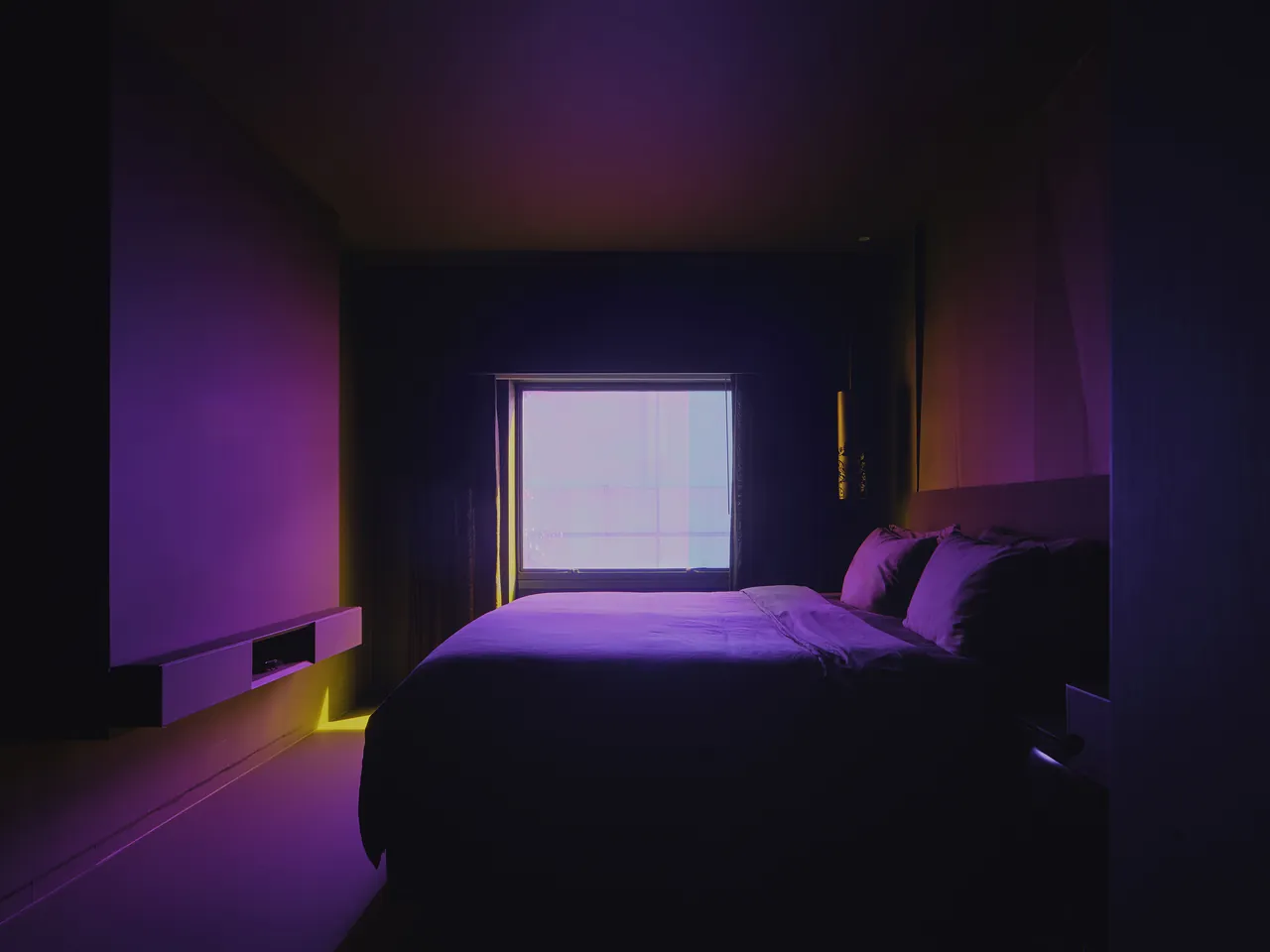 The matte-black guest room, lit only by the window
